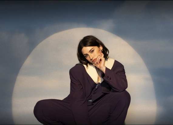 American singer-songwriter: Gracie Abrams sitting in a sign looking like a moon